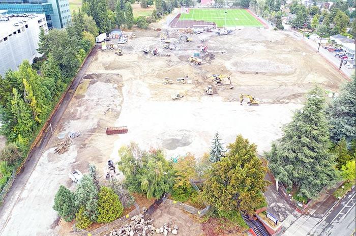 a construction site with construction equipment and trees