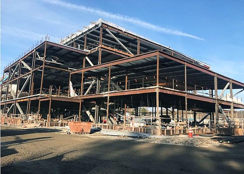 a four-story steel frame rises above the soil at a construction site