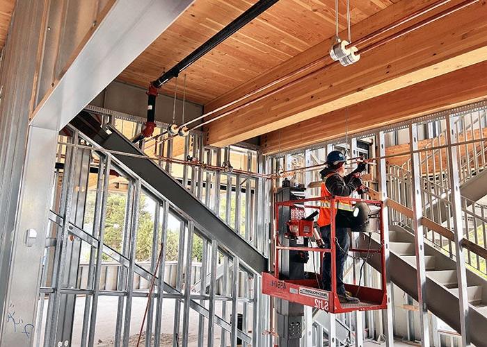 a person is on a lift working on copper pipes near the wooden ceiling and beams