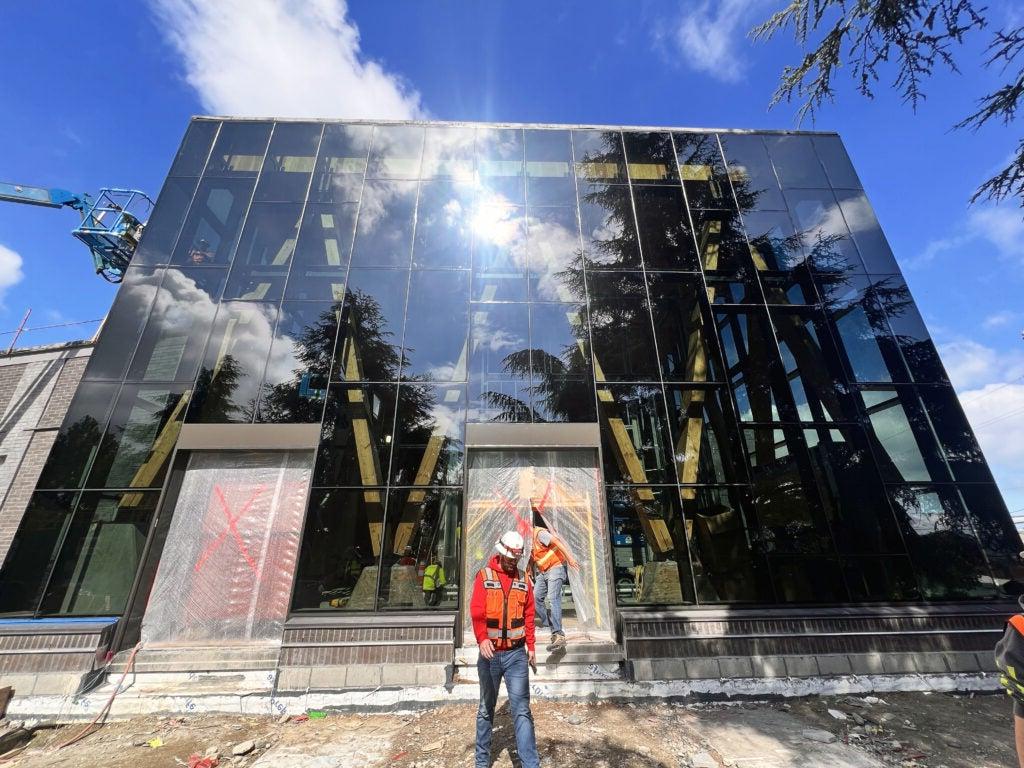 a two story glass wall exterior with holes for doorways covered in plastic